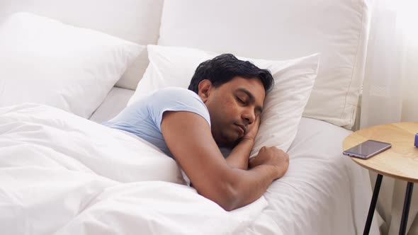 Indian Man Awaking and Stretching in Bed at Home