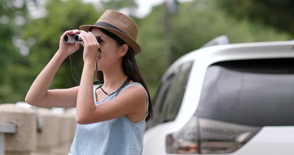 Woman travel with her car and looking though the binocular and enjoy natural landscape 