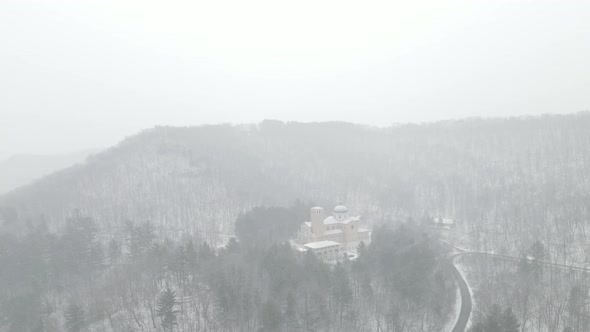 Amazing view of snow falling over mountain in Wisconsin with church building nestled in pine trees.