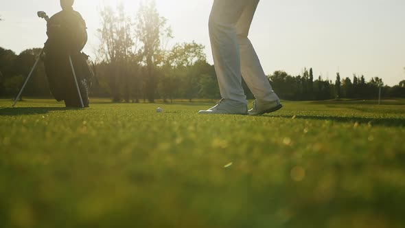 Golfer striking ball during sunset