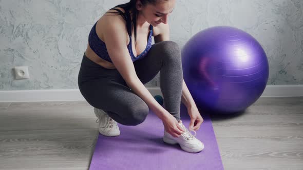 A Woman Ties Shoelaces on Sneakers