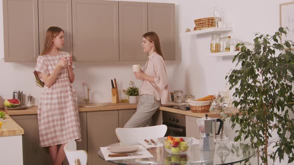 Identical Sisters Chatting in Kitchen