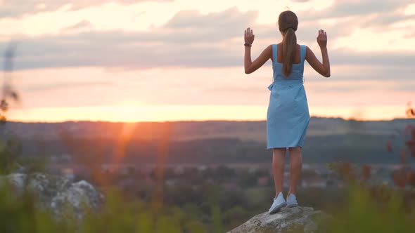 A Young Woman in Summer Dress Raising Up Her Hands Standing Outdoors Enjoying View of Bright Yellow