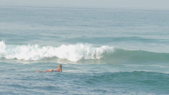 Tourist with Slim Body Surfs and Floats on Strong Ocean Wave