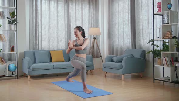 Young Asian Athletic Female Exercising, Stretching And Practicing Yoga On The Mat At Home