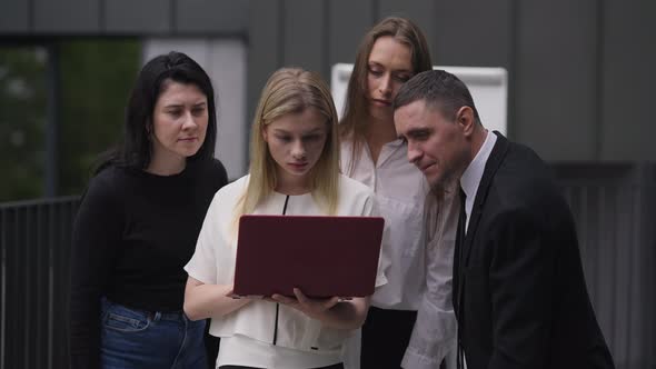 Medium Shot of Young Caucasian Woman Checking Ebusiness Success with Group of Colleagues