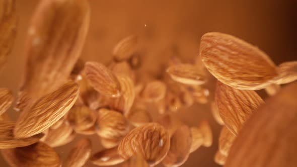 Super Slow Motion Detail Shot of Almonds Falling Down on Brown Background at 1000 Fps