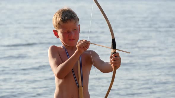 Boy on the Beach is Loading Arrows Into a Bow