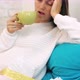 Sick young woman sits of sofa and drinks hot beverage at home - VideoHive Item for Sale