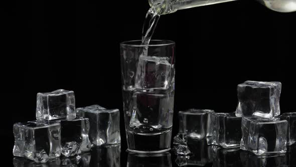 Pouring Up Shot of Vodka From a Bottle Into Glass. Black Background