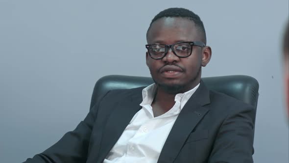 Dark-skinned Businessman Sitting at Table and Communicating with His Caucasian Personal Assistant