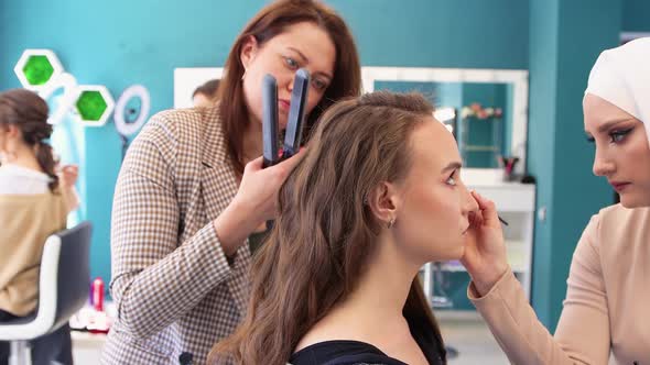 The Girl Has Two Masters Dye Her Eyelids and Curl Her Hair at the Same Time