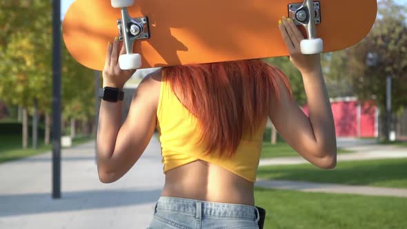 Young Beautiful Woman with Skateboard is Walking Outdoors Slow Motion