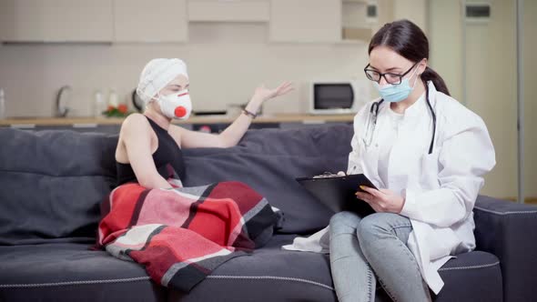 Concentrated Female Doctor in Eyeglasses and Covid Face Mask Taking Medical History of Patient in