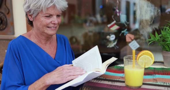 Senior woman reading a book at bar outdoor