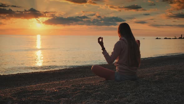 Girl Having Meditation Over the Sea Before Sunset