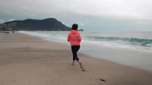 Lonely woman runs on empty beach