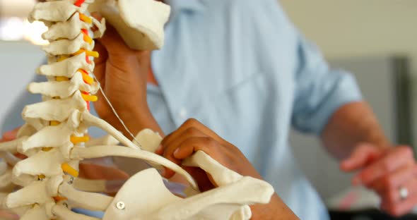 Caucasian male teacher fixing human skeleton model in classroom at school 4k