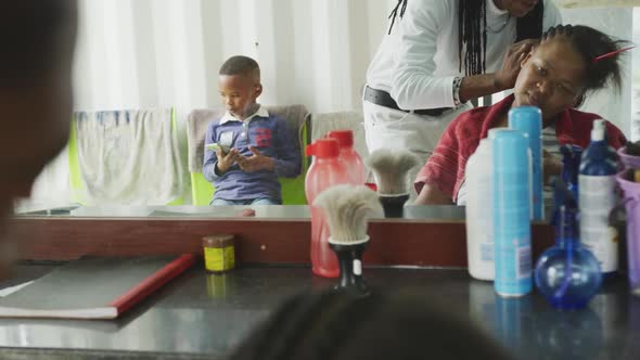 African woman at the hairdresser while boy waiting