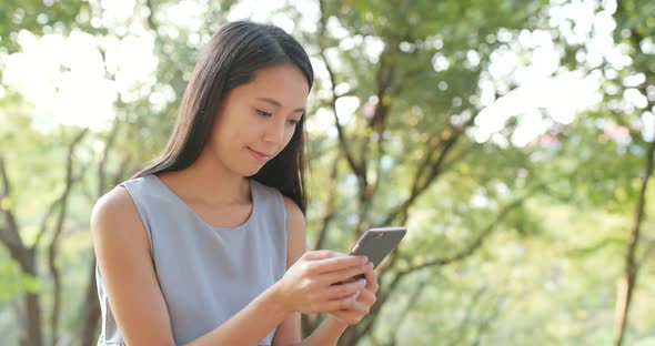 Woman looking at smart phone in the park 