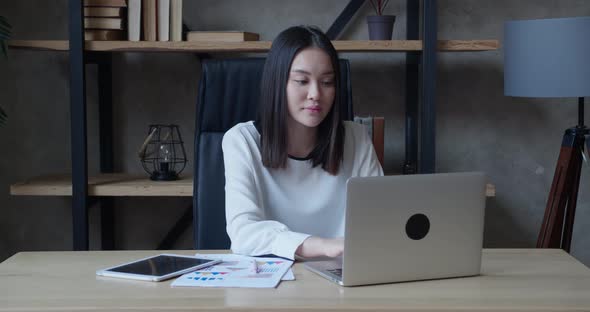 Asian Attractive Female Office Worker Sitting at the Laptop Typing the Text on Computer and Say Wow
