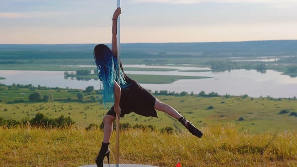 Pole Dance on Nature - Sexy Woman with Blue Braids in Black Clothes Spinning on the Pole Wearing