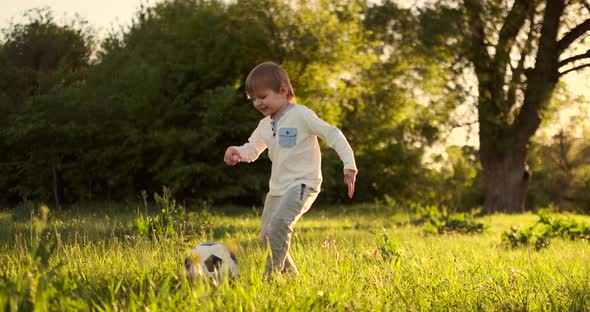 Happy Boy Running with Soccer Ball Running at Sunset in Summer Field