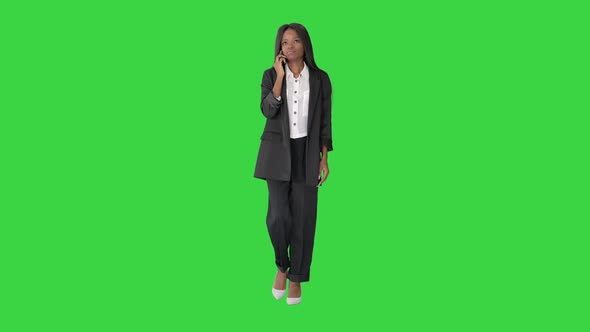 Casual African American Businesswoman Talking on Phone While Walking on a Green Screen, Chroma Key.