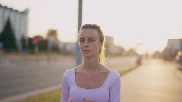 A Young Woman Runner is Training in the Summer Within a City