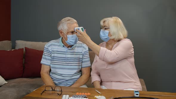 Senior Couple Measures Temperature with Contactless Digital Thermometer During Coronavirus Lockdown