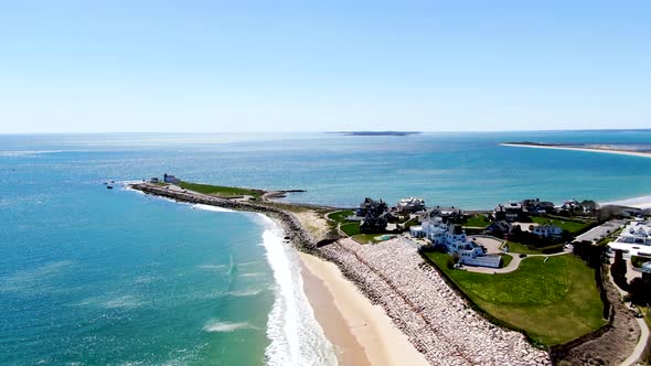 Luxury coastal town surrounded by sandy beach and blue ocean on sunny day, aerial drone view