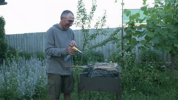 Man using gas spray for fire flames in grill. Male with gasoline spray ignitioning bonfire in grill