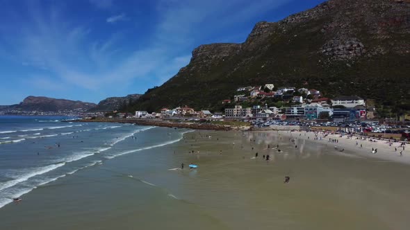 Side drone shot of surfers at Muizenberg beach, Cape Town - docents of surfers trying to catch a wav