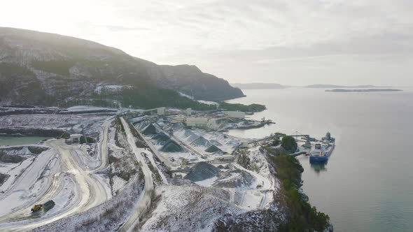 Cargo Ship Docked At Aggregate Quarry With Open Pit Stockpile, Aerial