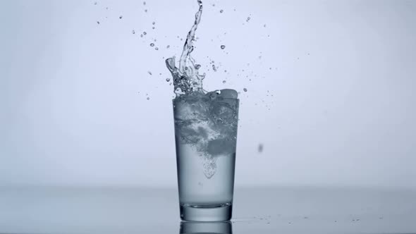 Slo-motion ice cubes falling into glass