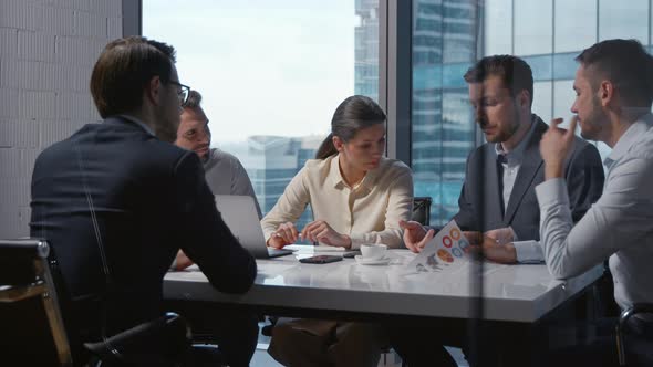 Young businessman in a suit explaining company financial statistics to a team of colleagues