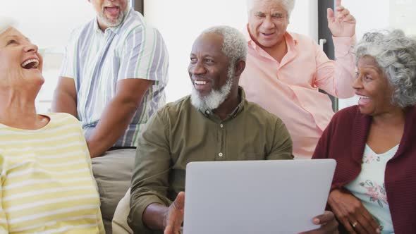 Happy senior diverse people talking and using laptop at retirement home