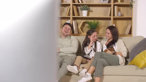 Joyous Family Laughing and Petting Cats while Watching TV at Home