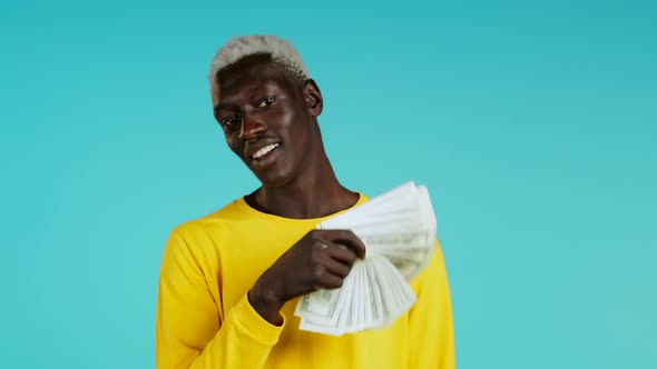 Amazed Happy Excited African Man Showing Money - U.S. Currency Dollars Banknotes on Blue Wall