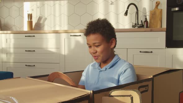 Happy School Age Black Boy Playing with Toy Cardboard Car and Showing Car Keys