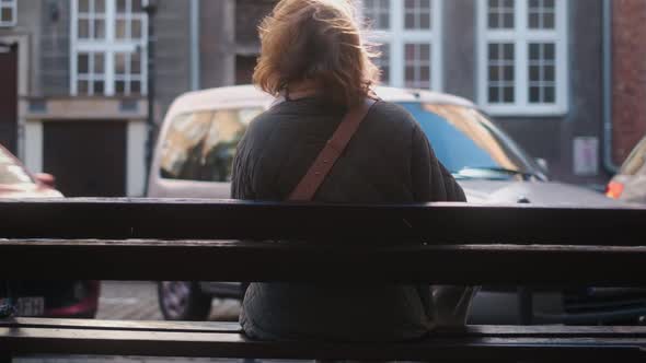 Rear View Woman Sits to the Bench in the Street of Old Town  60p