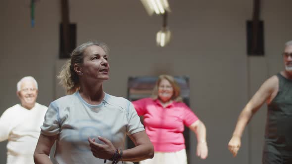 Cheerful Dance Teacher Dancing with Senior People in Ballroom