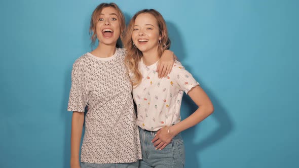 Two young beautiful smiling hipster girls in trendy summer clothes