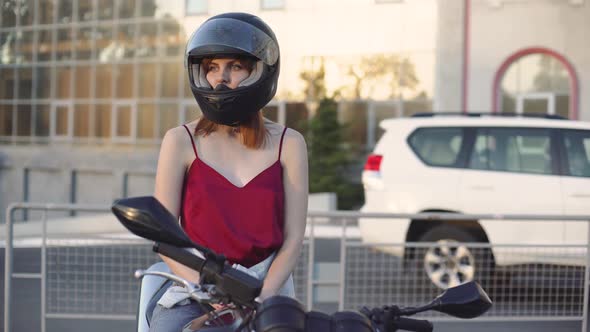 Beautiful Young Redhaired Woman Motorcyclist with Her Motorcycle and Helmet