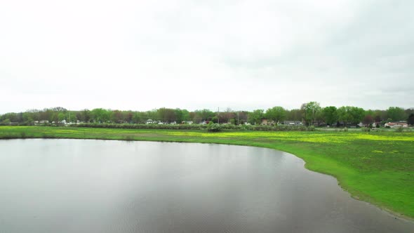 Aerial Drone Shot of Lake Flying Towards Highway and Residential Community with a Meadow in Between