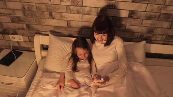 Happy Caucasian Mother Resting with Daughter Watching Learning Video on Smartphone App
