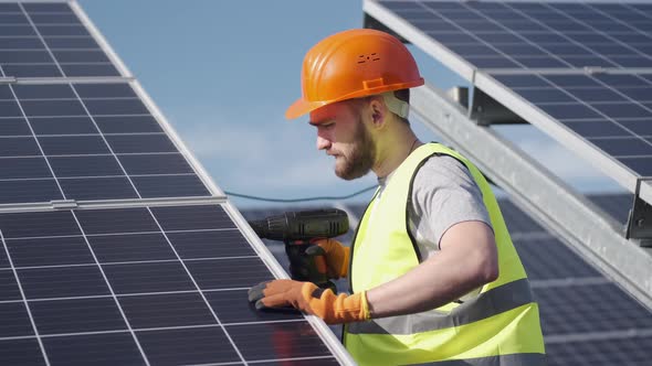 Male Engineer in a Uniform Is Checking the Solar Battery Outside