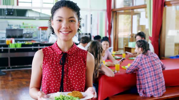 Portrait of happy schoolgirl holding breakfast in plate