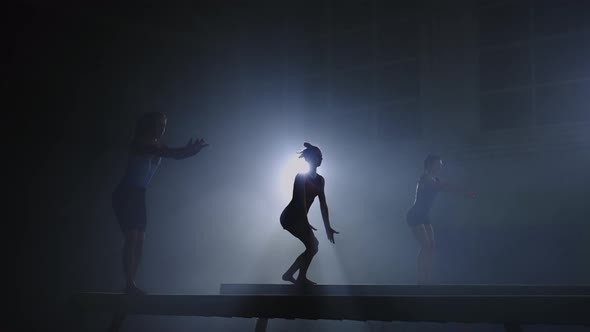 Junior Competition By Artistic Gymnastics Silhouettes of Three Sporty Girls on Balance Beams