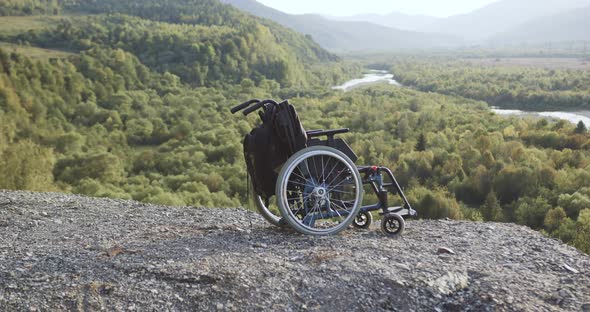 Close Up of Medical Wheelchair with Backpack Which Posing on the Top of Hill Among Beautiful Nature